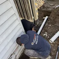 Plumber working on outdoor drainage pipework, Elwood