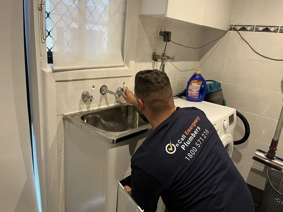 Plumber inspecting laundry sink plumbing, Elwood